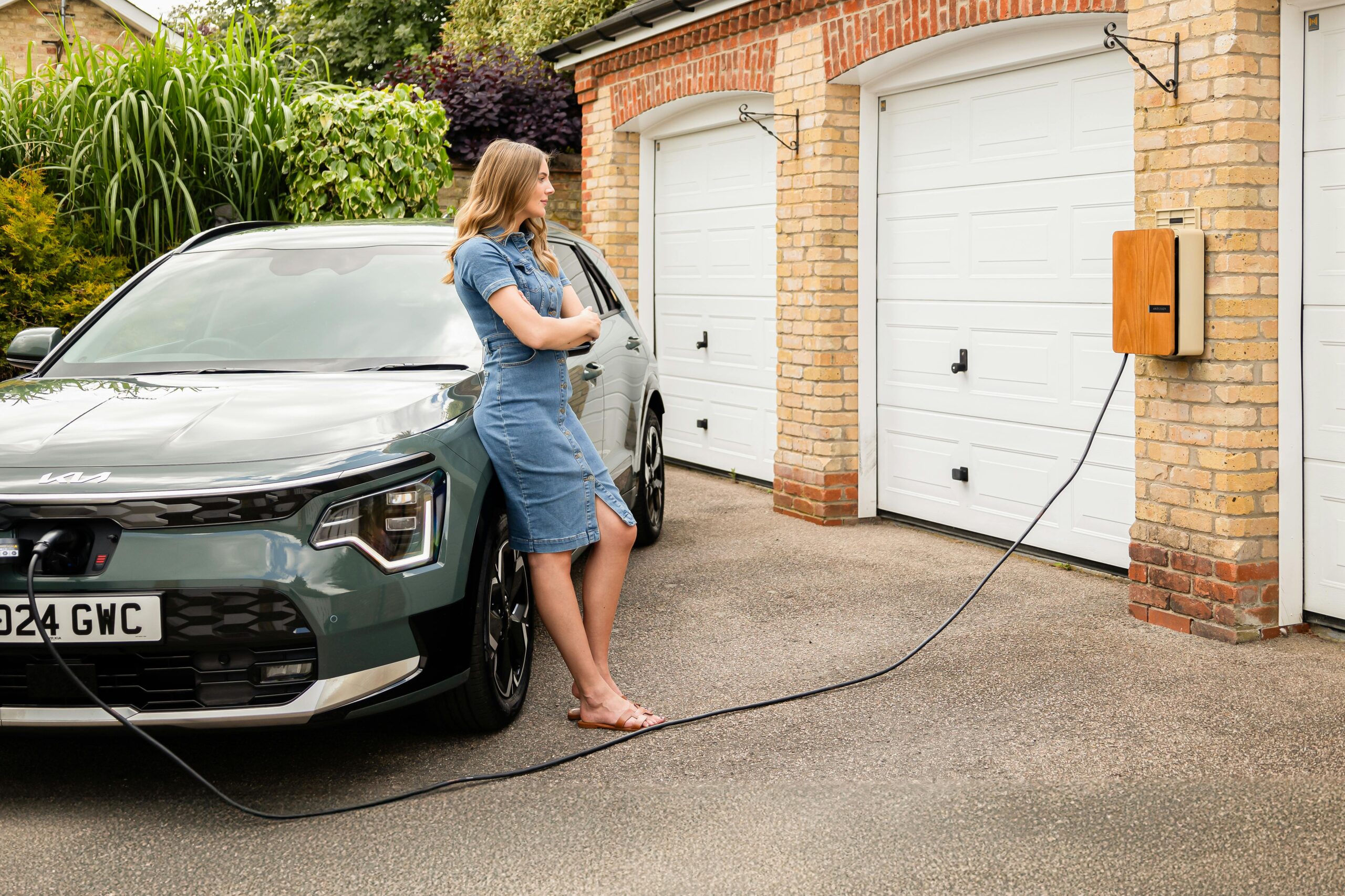 Woman Waiting For Charge A woman waiting for her EV to charge using a home charger.