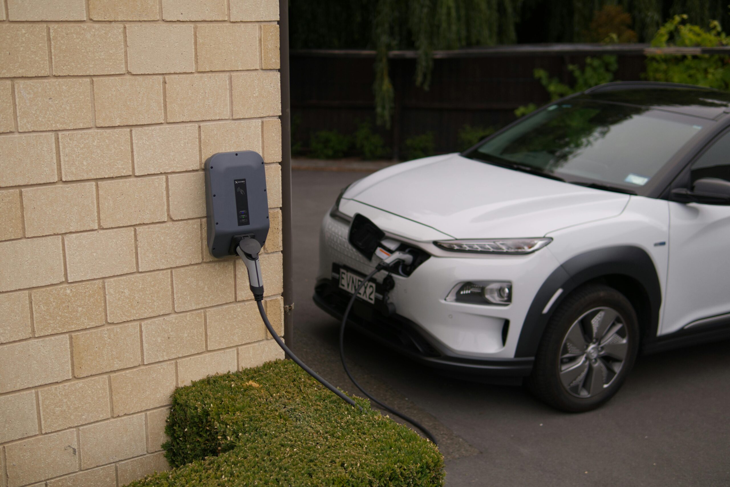 White EV Plugged In A white EV plugged in to a home EV charger.