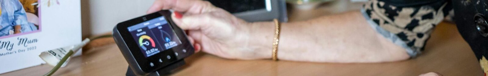 An old person holding their smart meter in the cost of living crisis.
